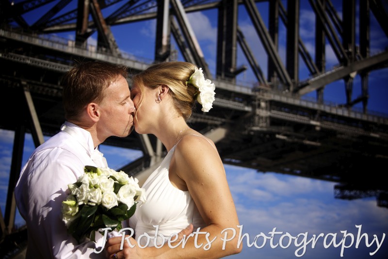 Bride and groom kissing in front of the Sydney Harbour Bridge - wedding photography sydney